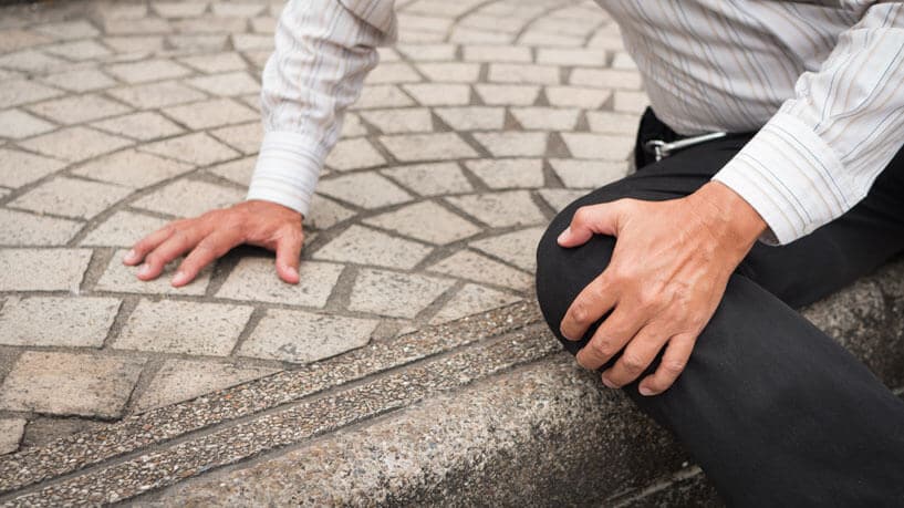A man grasps his knee after tripping on an unsafe surface. Slip-and-fall incidents are a major cause of personal injury.