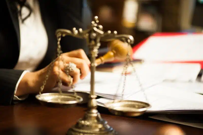 Lawyer working at desk with scales of justice in foreground.