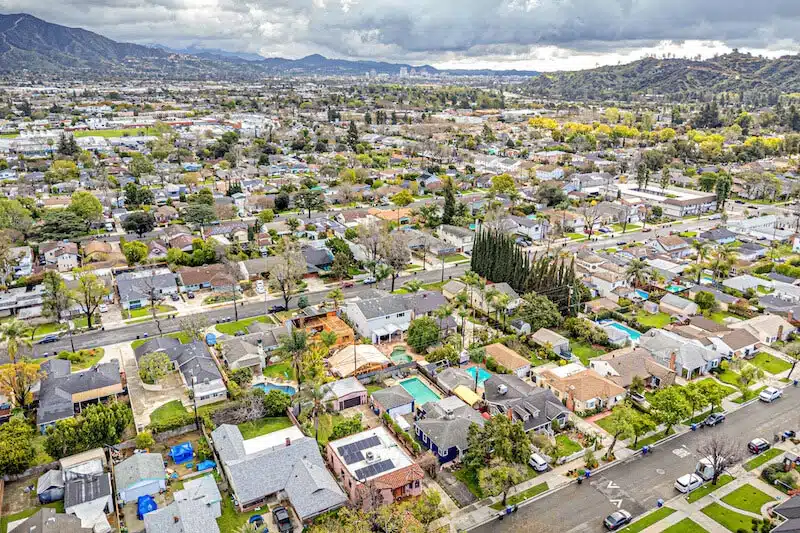 Aerial view of a city skyline and freeway with mountains in the background.