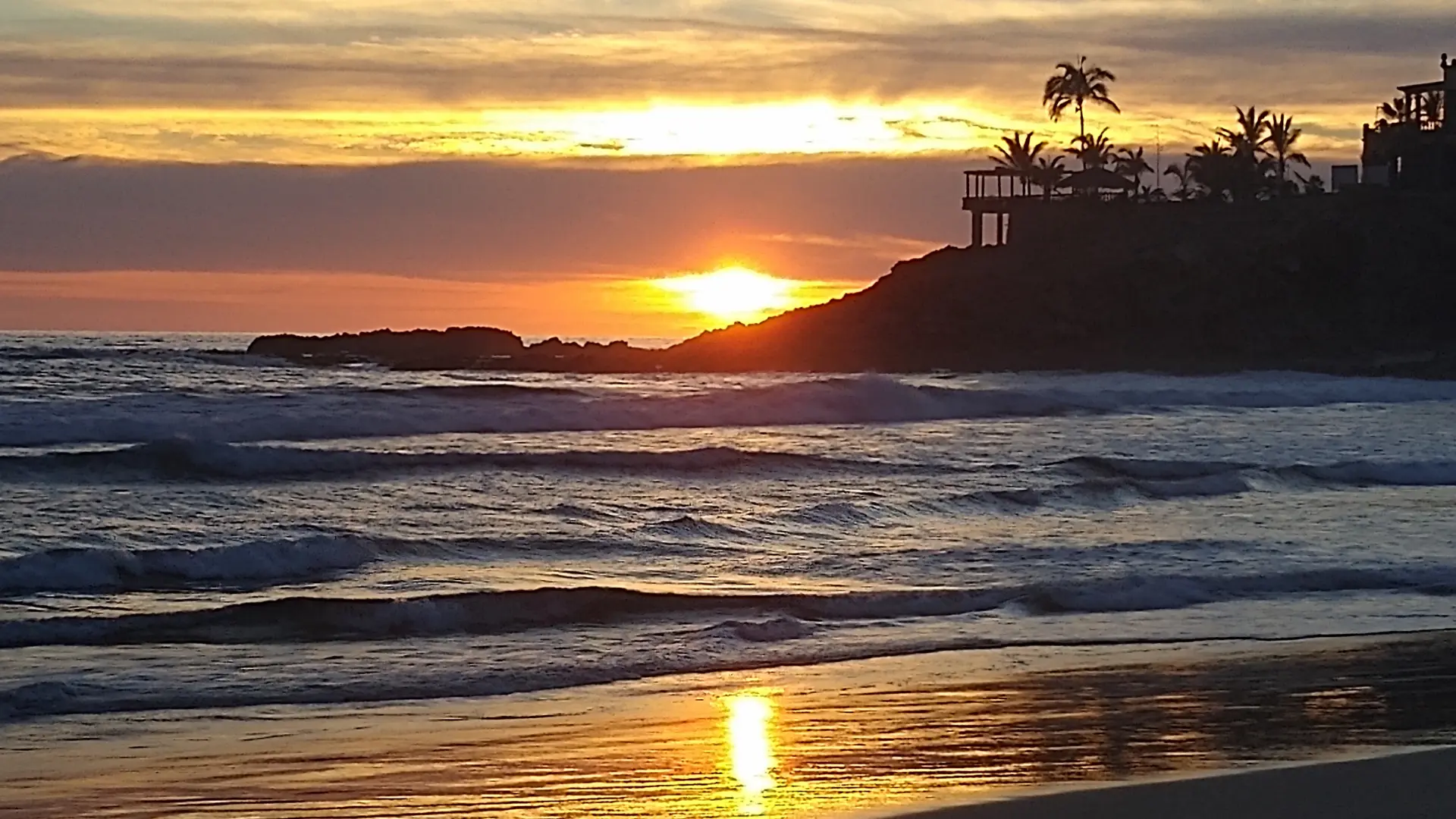 Ocean waves and sunset over a coastal beach.