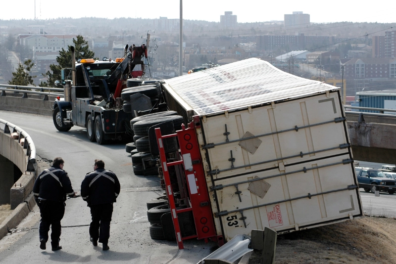 An overturned truck lies on its side, with debris scattered around, indicating a recent accident.